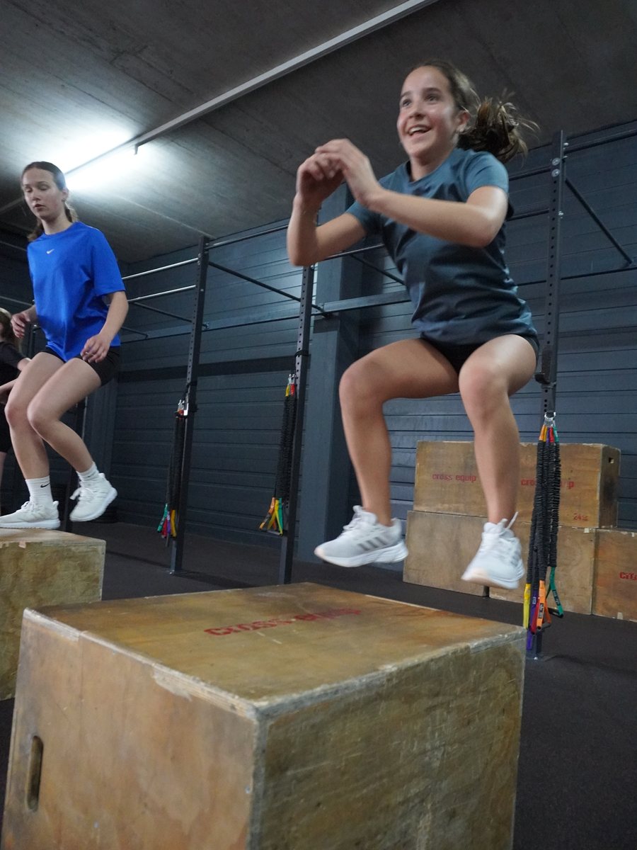 Teens doing box jumps in a class at 1352 Athletics